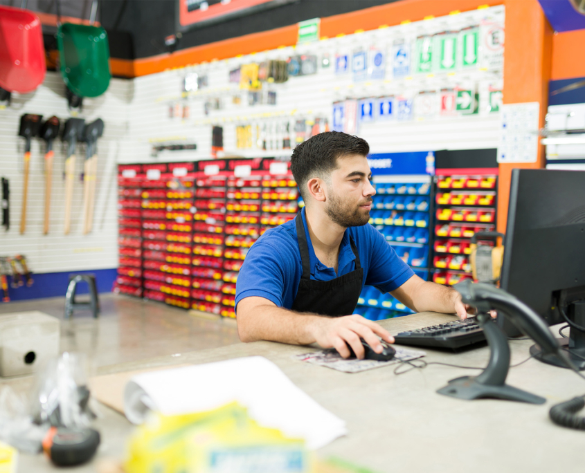 Side view of man sitting on computer in hardware store